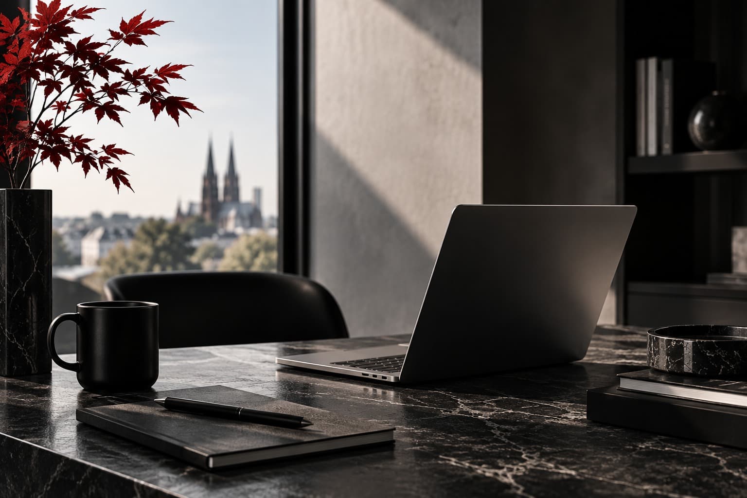 Offener Laptop auf einem dunklen Schreibtisch mit Notizbuch, Kaffeetasse und rotem Ahornzweig, im Hintergrund die Kölner Skyline.